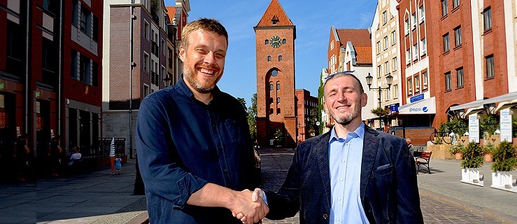 Adrian Zandberg i  Robert Koliński na tle Bramy Targowej w Elblągu,