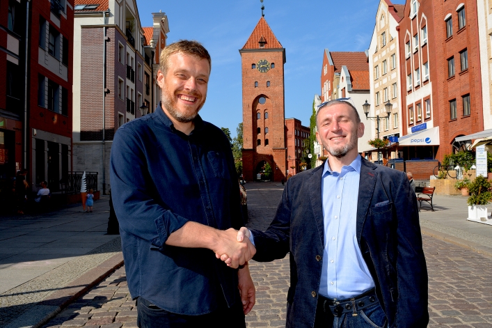 Adrian Zandberg i  Robert Koliński na tle Bramy Targowej w Elblągu,